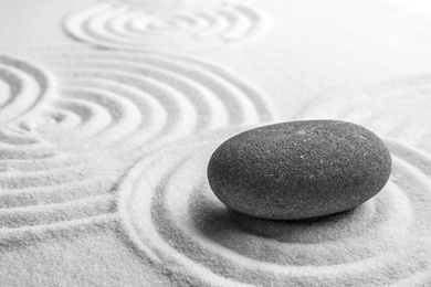 Photo of Grey stone on sand with pattern, space for text. Zen, meditation, harmony