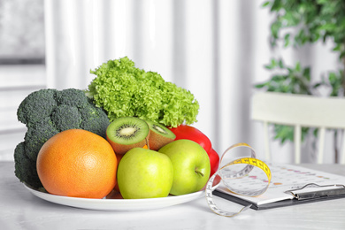 Photo of Measuring tape, vegetables and fruits on table. Diet plan from nutritionist