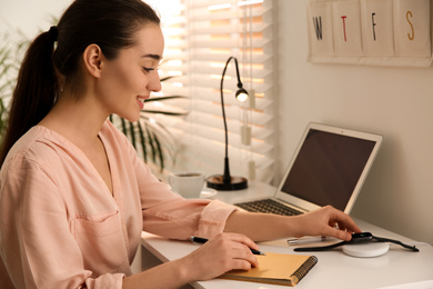 Photo of Woman putting smartwatch onto wireless charger at white table. Modern workplace accessory