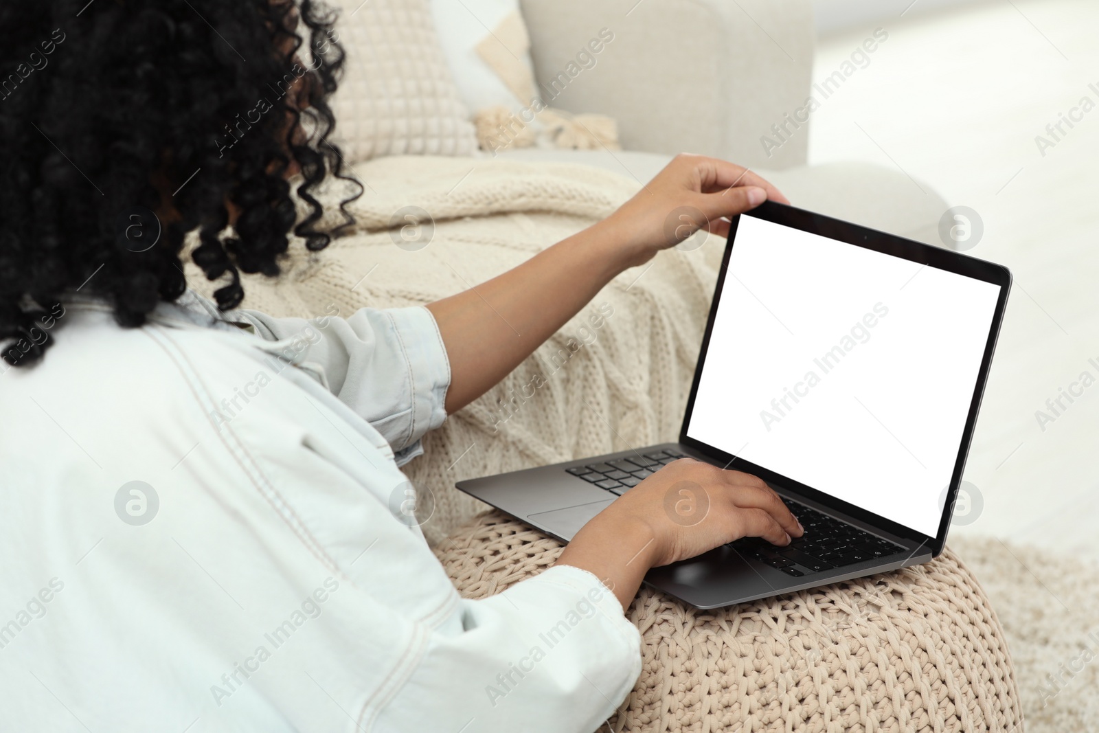 Photo of Woman using laptop on pouf at home, closeup. Space for text