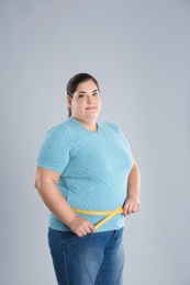 Overweight woman measuring waist before weight loss on color background