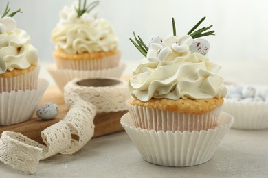 Tasty Easter cupcakes with vanilla cream and ribbon on gray table