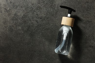 Photo of Bottle of cosmetic product on wet grey background, top view. Space for text