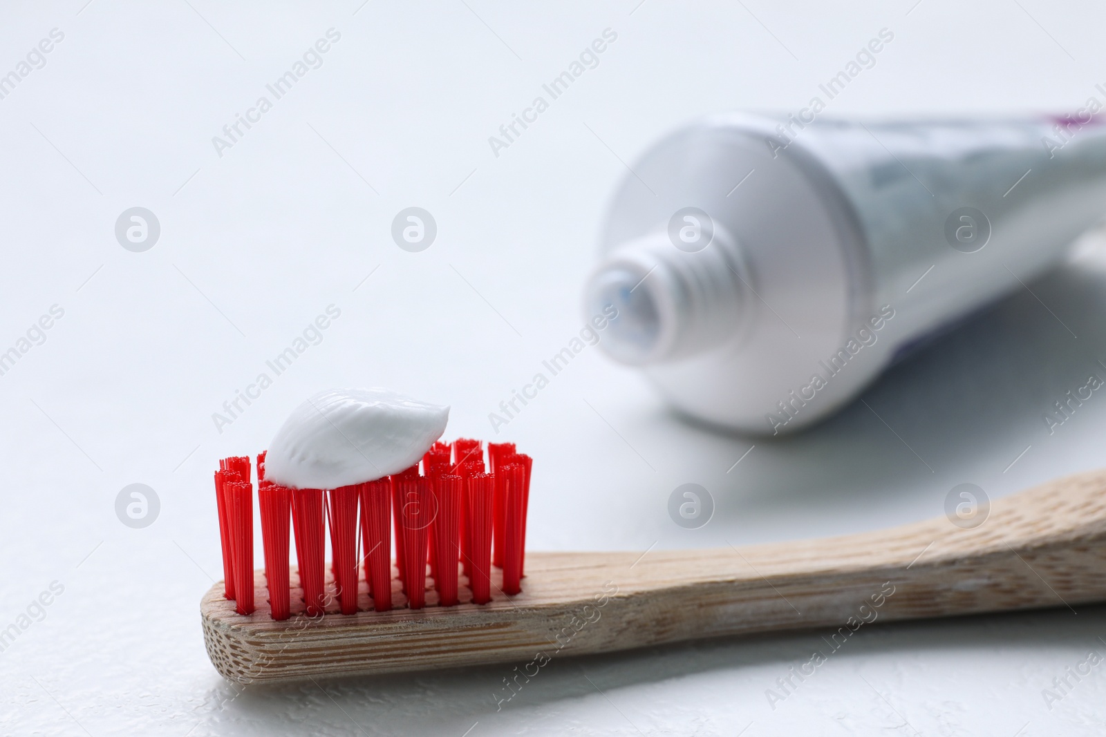 Photo of Brush with toothpaste and tube on white background, closeup