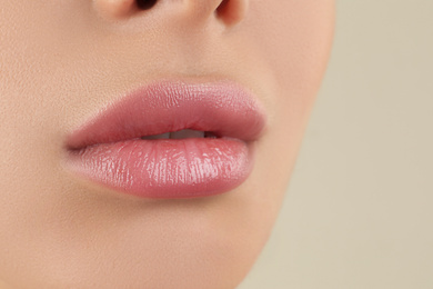 Woman with beautiful full lips on beige background, closeup