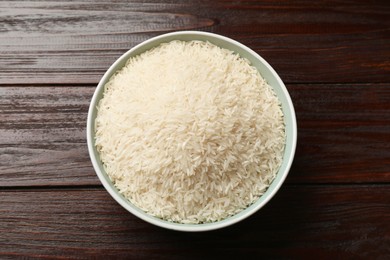 Photo of Raw basmati rice in bowl on wooden table, top view