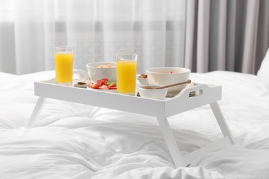 Photo of Tray with tasty breakfast on bed at home