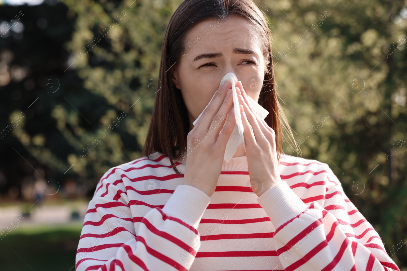 Photo of Woman with napkin suffering from seasonal allergy outdoors