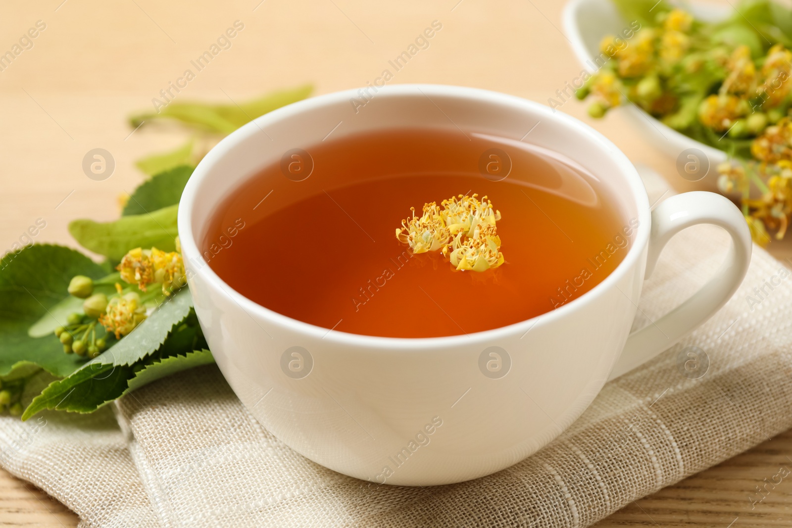 Photo of Cup of tea with linden blossom on table, closeup