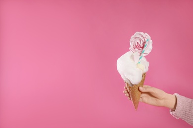 Woman holding tasty cotton candy dessert on pink background, closeup. Space for text