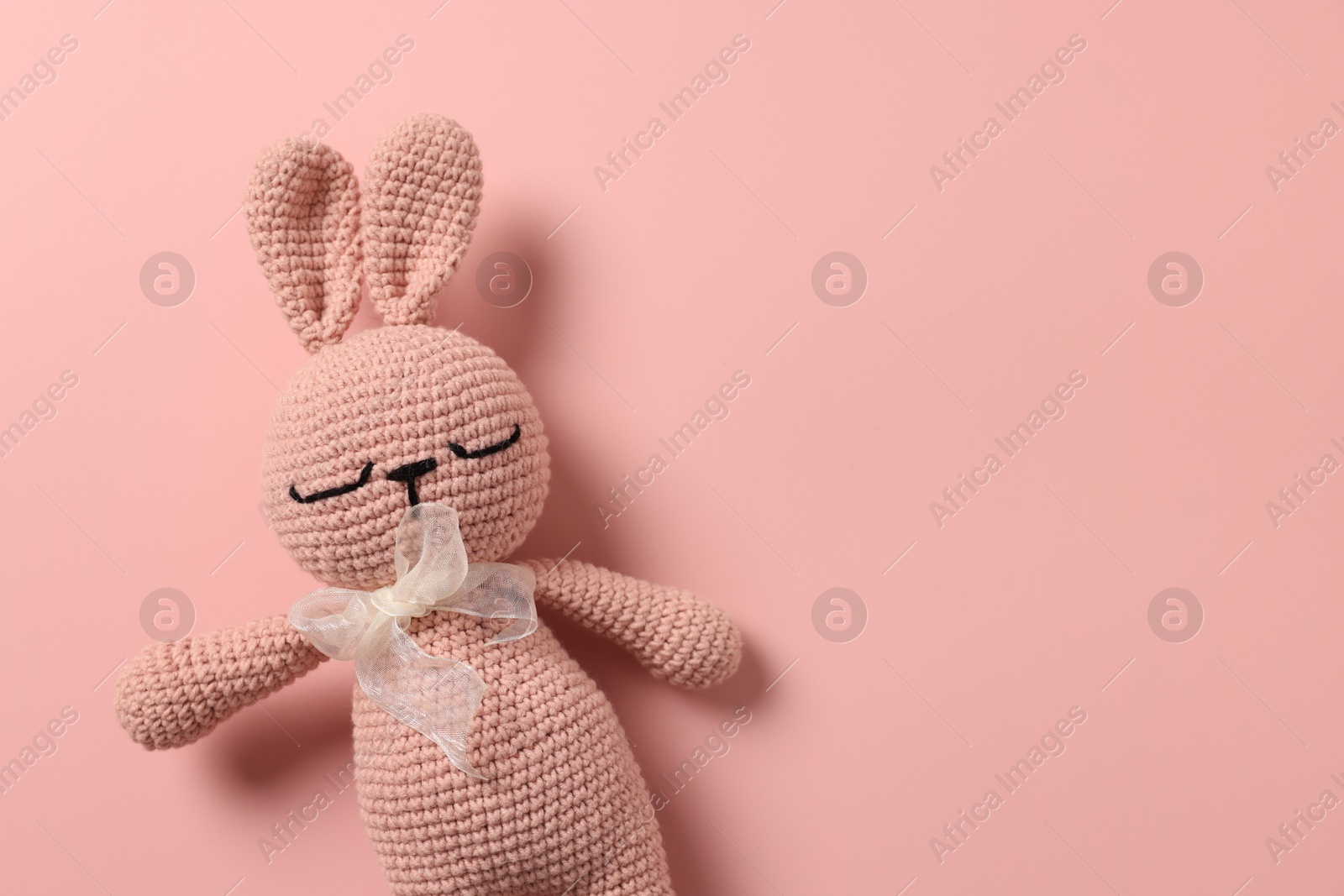 Photo of Baby accessory. Toy rabbit on pink background, top view. Space for text