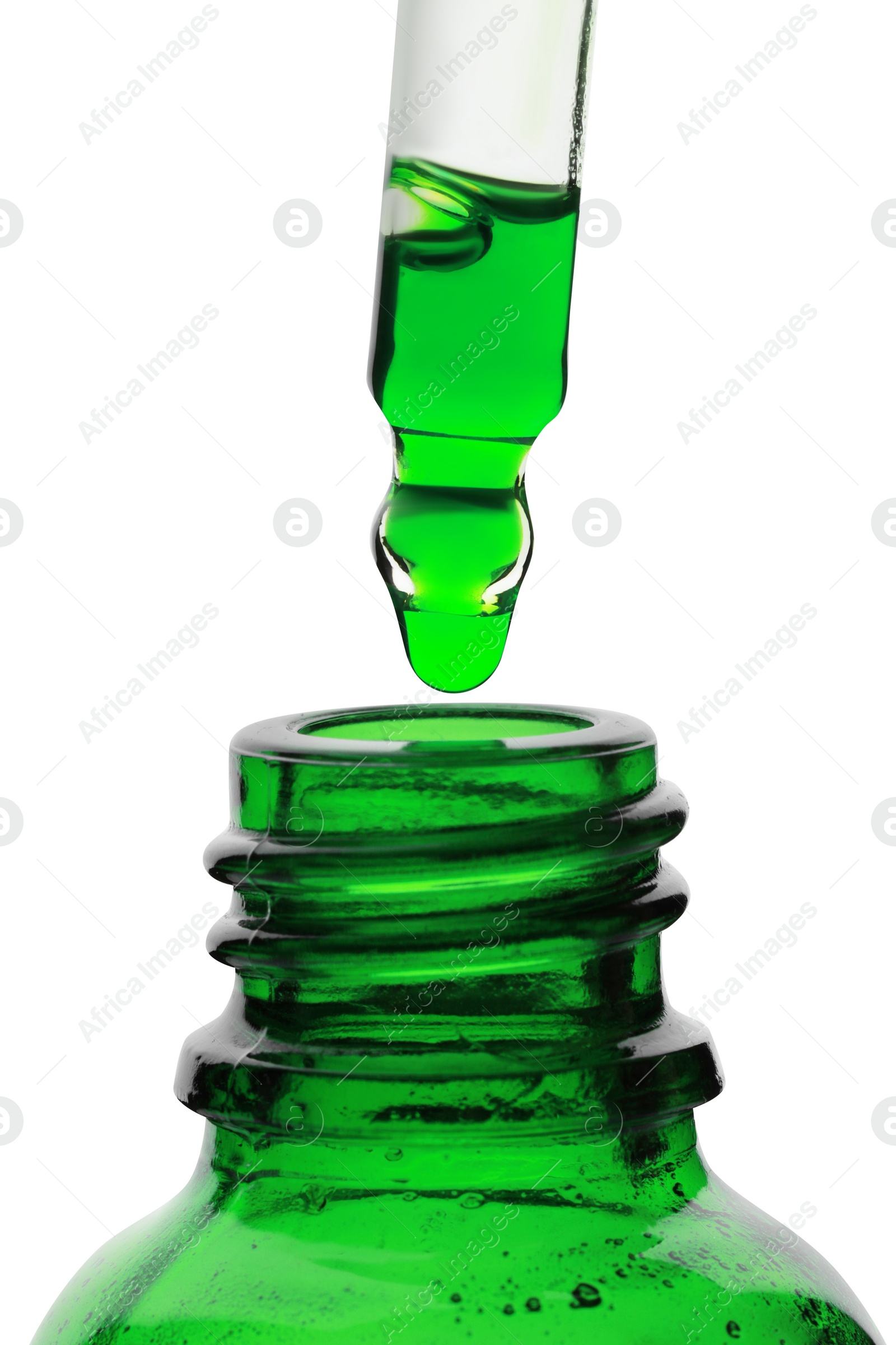 Photo of Dripping green facial serum from pipette into glass bottle on white background, closeup