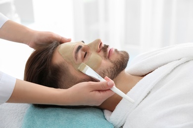 Cosmetologist applying mask on client's face in spa salon