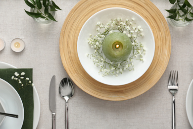 Elegant table setting with green plants on light cloth, flat lay