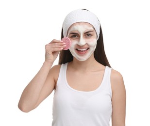 Photo of Young woman with headband washing her face using sponge on white background