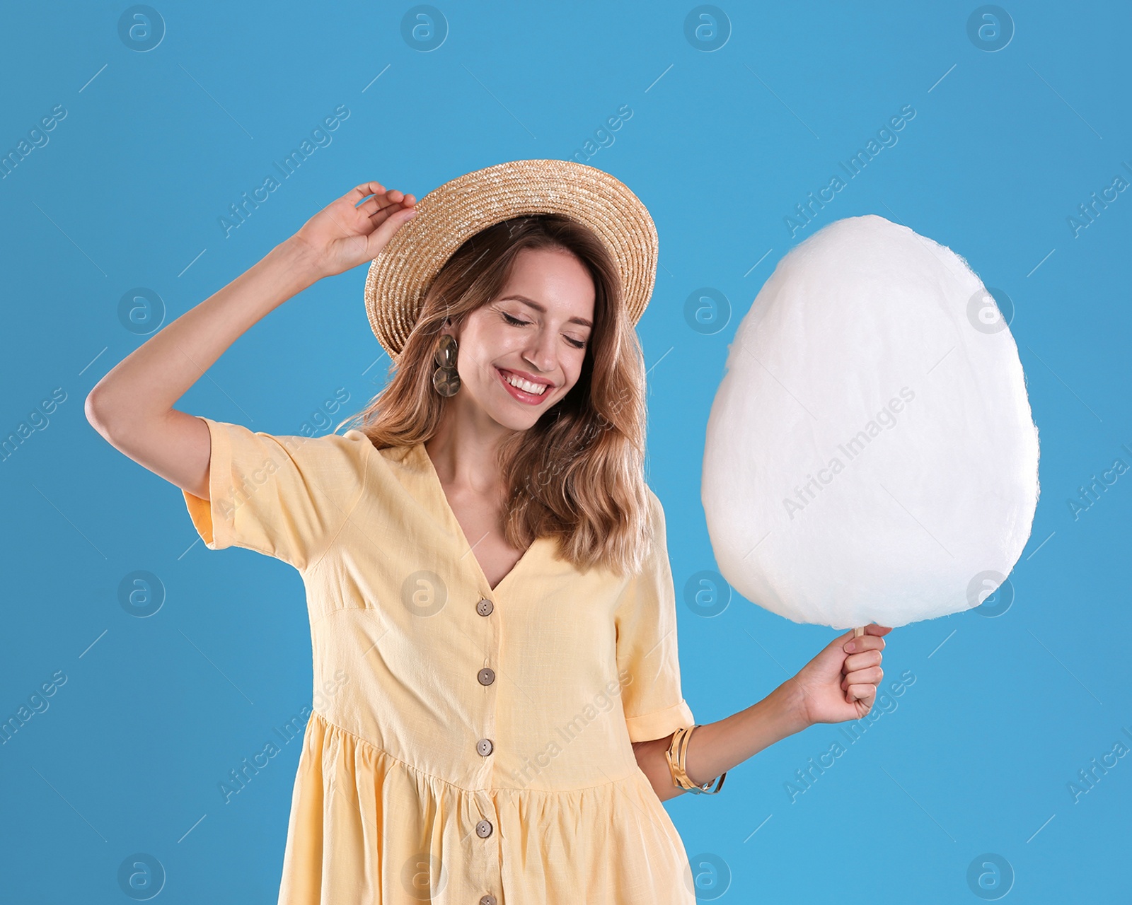 Photo of Happy young woman with cotton candy on blue background