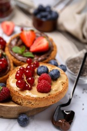 Photo of Tasty organic rusks with different toppings and ingredients on white marble table, closeup