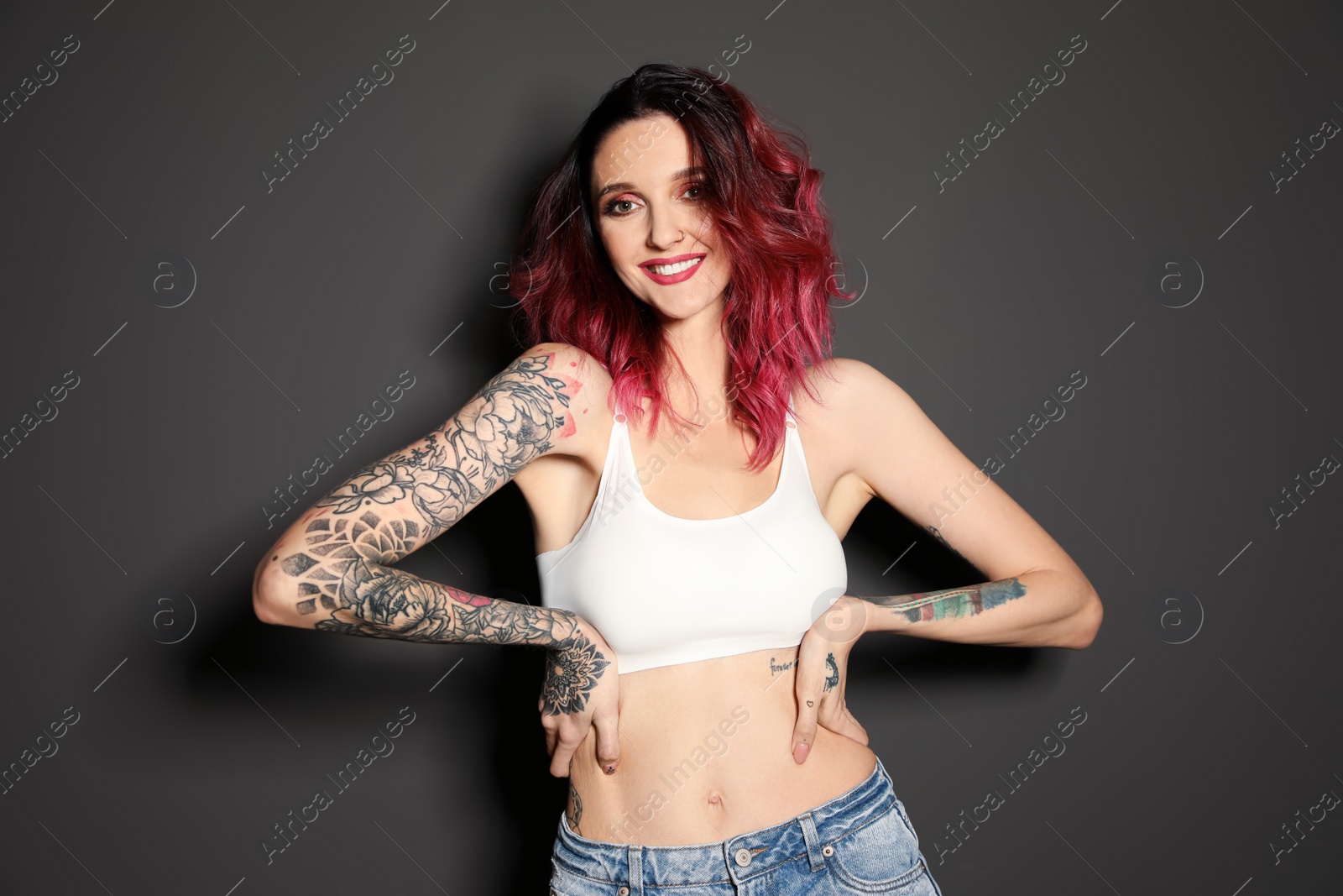 Photo of Beautiful woman with tattoos on body against black background