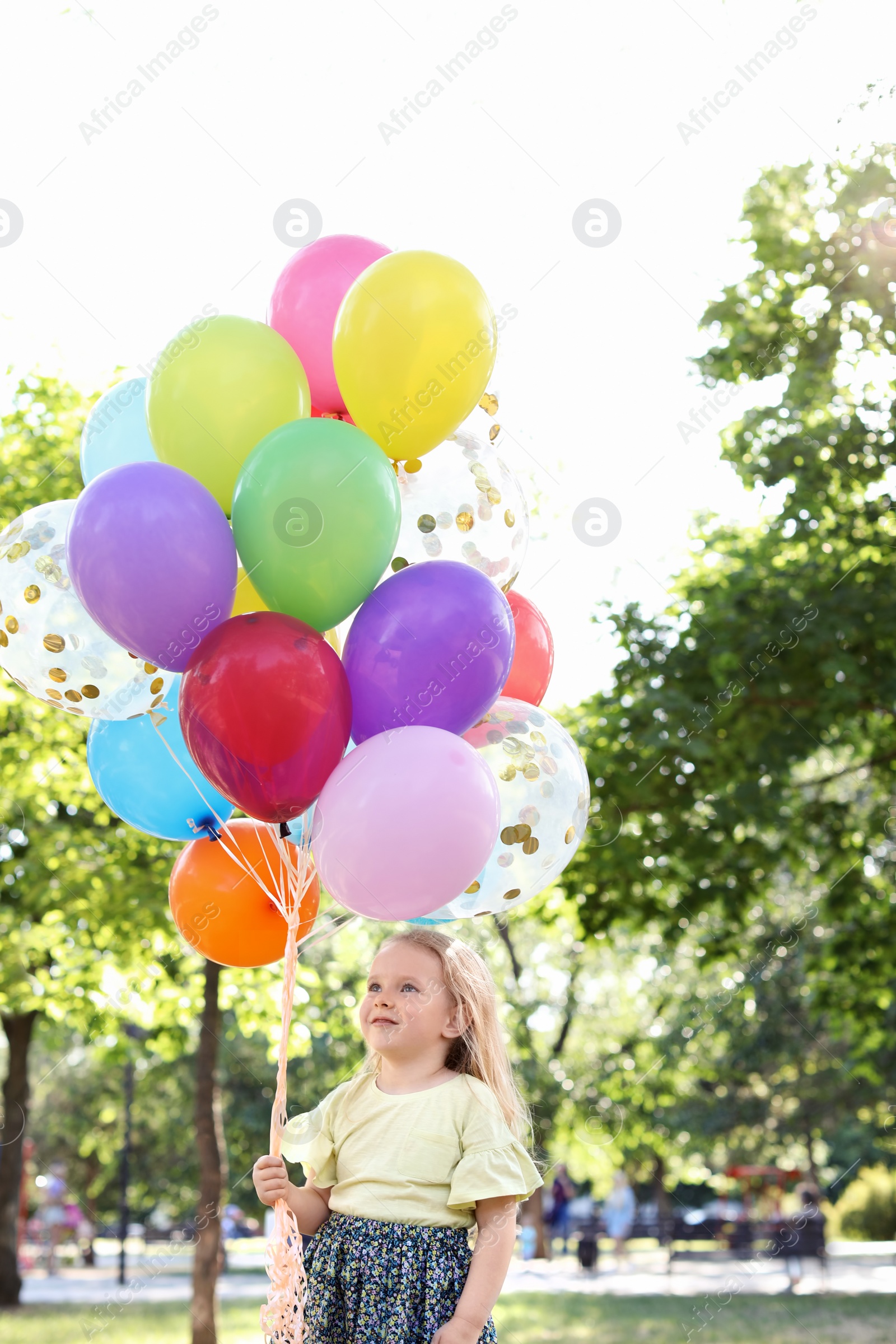 Photo of Cute little girl with colorful balloons outdoors on sunny day