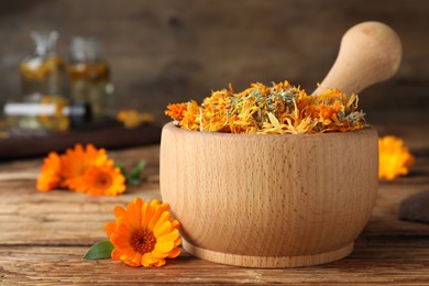 Mortar of dry calendula and fresh flowers on wooden table