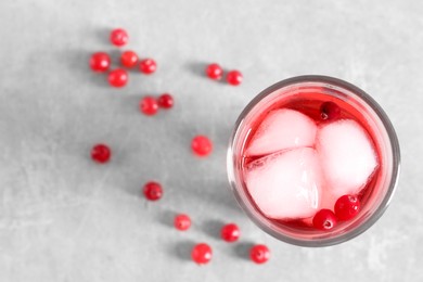 Tasty cranberry juice with ice cubes in glass and fresh berries on light grey table, top view