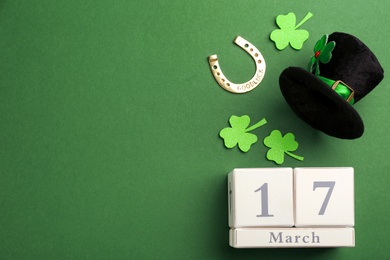 Photo of Leprechaun's hat, block calendar and St. Patrick's day decor on green background, flat lay. Space for text