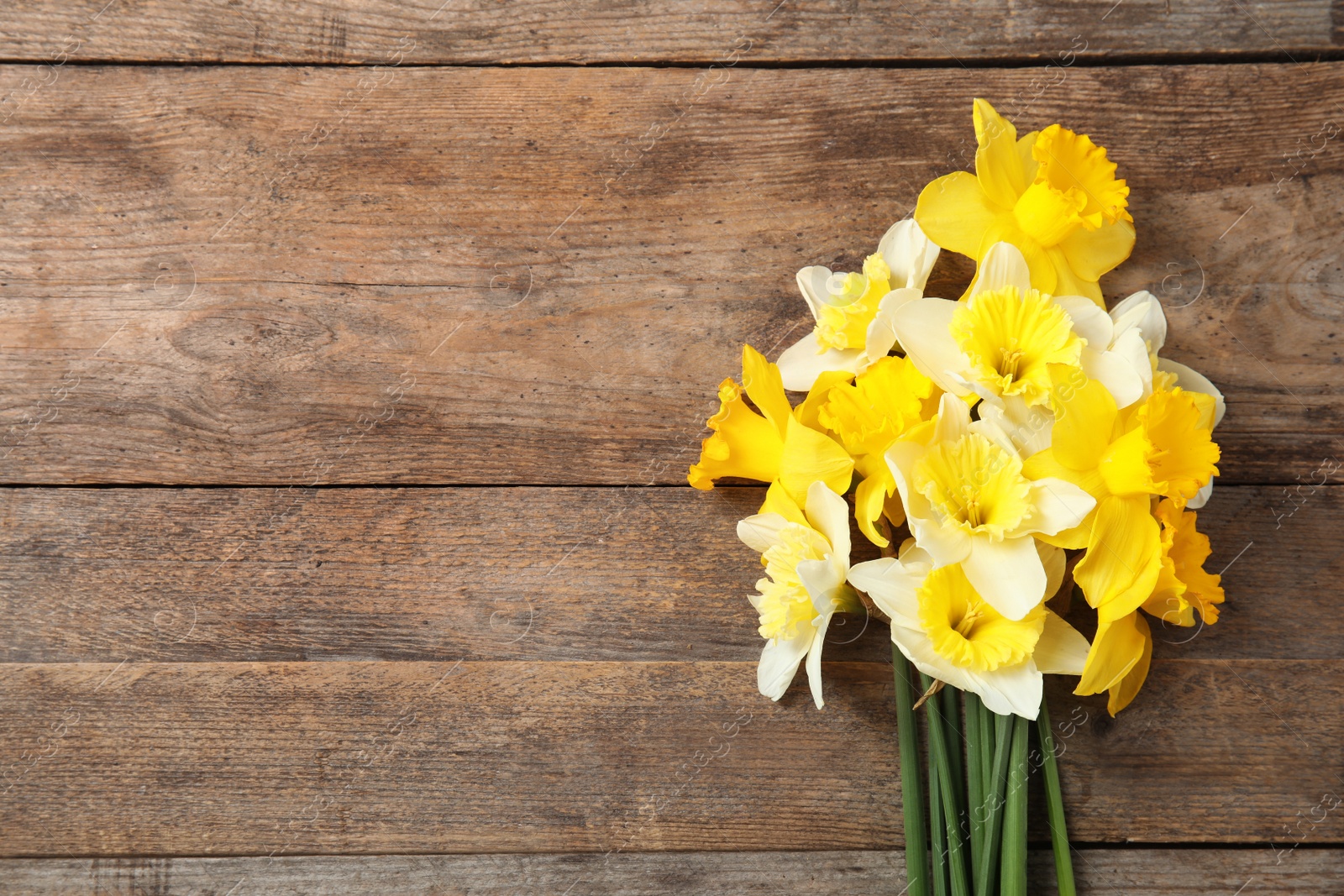 Photo of Bouquet of daffodils on wooden background, top view with space for text. Fresh spring flowers