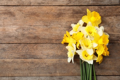 Photo of Bouquet of daffodils on wooden background, top view with space for text. Fresh spring flowers