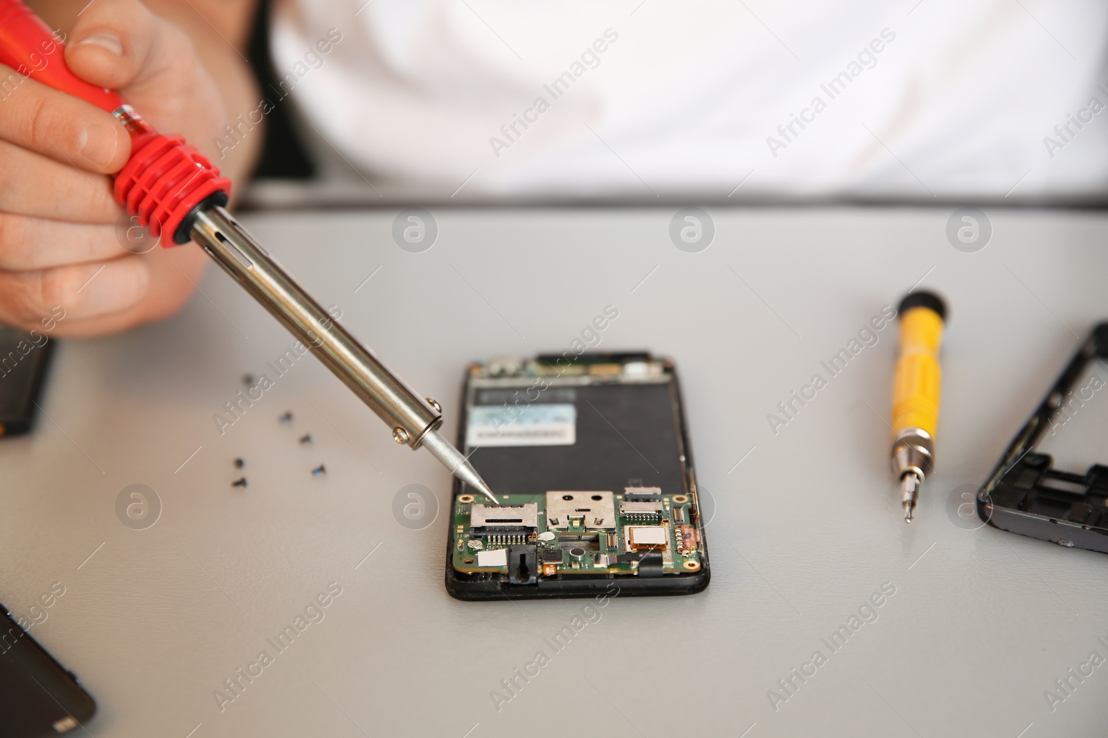 Photo of Technician repairing mobile phone at table, closeup