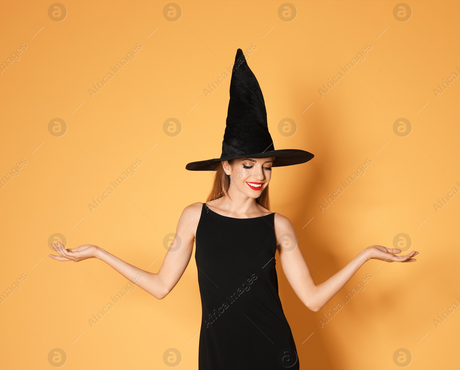 Photo of Beautiful woman wearing witch costume for Halloween party on yellow background