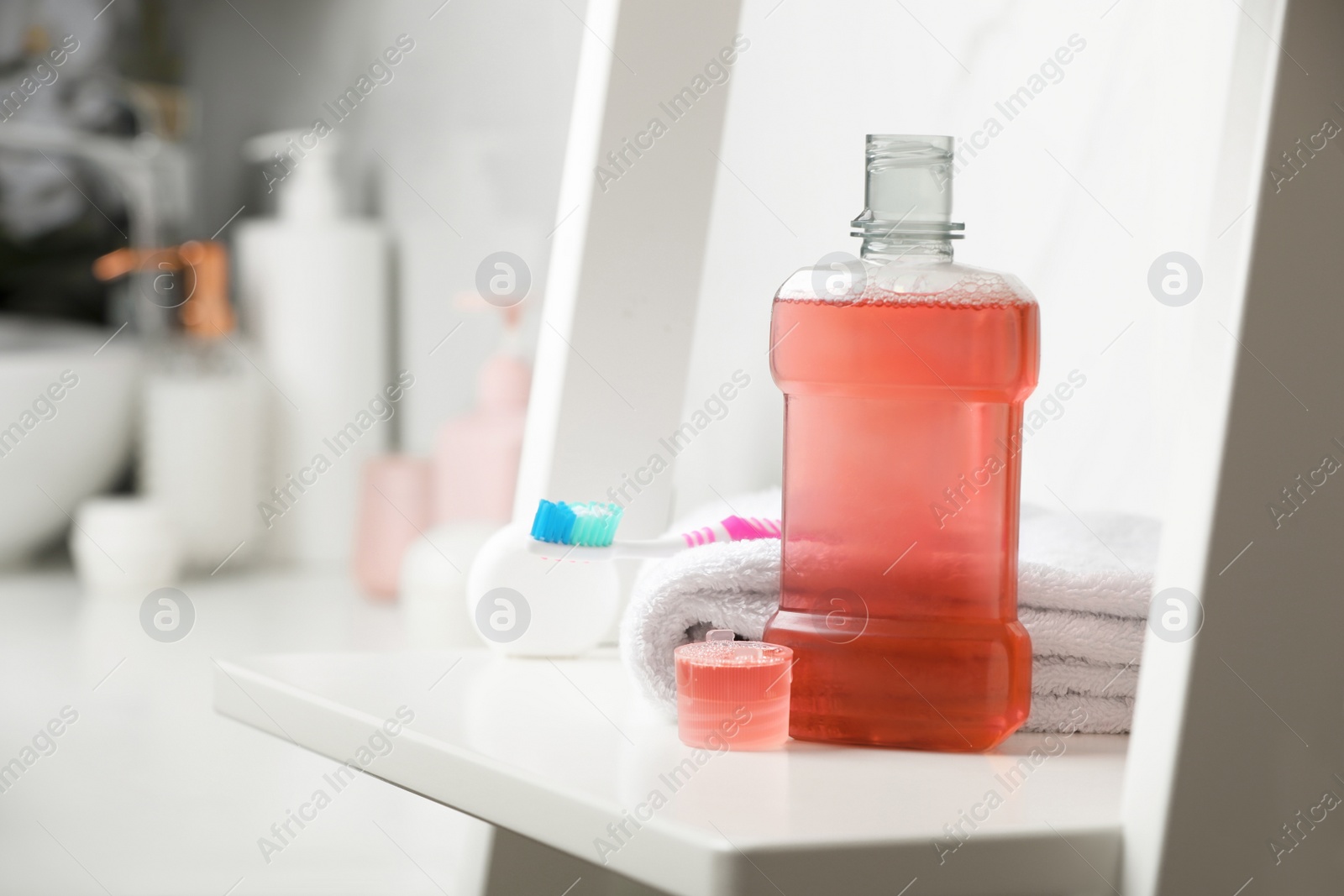 Photo of Bottle of mouthwash on white shelf in bathroom, space for text