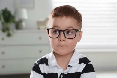 Photo of Emotional little boy in glasses at home