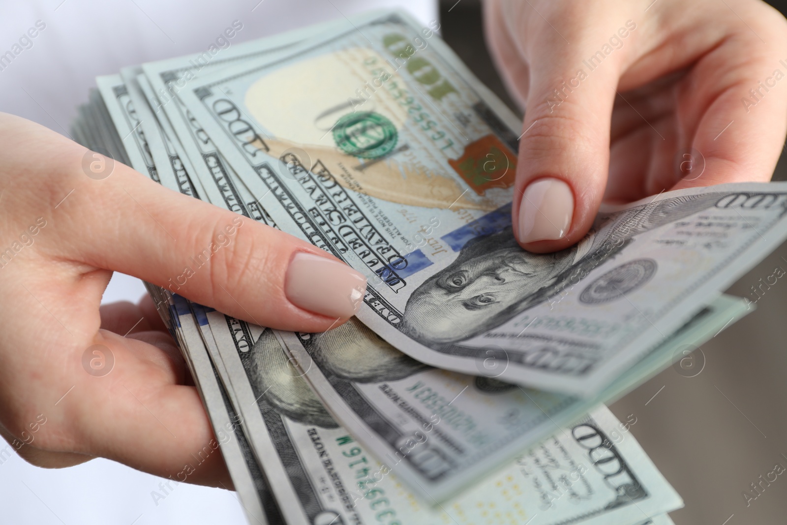 Photo of Money exchange. Woman counting dollar banknotes on grey background, closeup