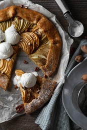 Photo of Delicious apple galette served with ice cream on wooden table, flat lay