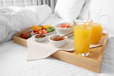 Photo of Wooden tray with tasty breakfast on bed at home