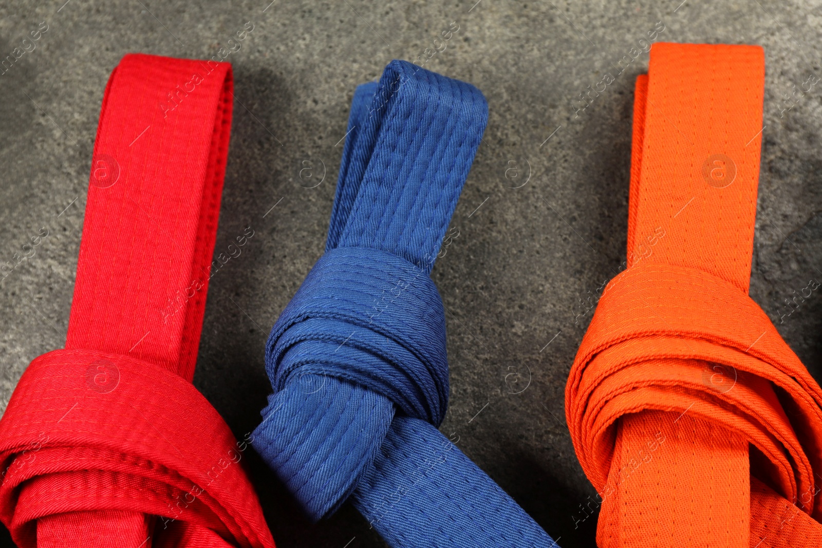 Photo of Colorful karate belts on gray background, flat lay