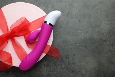 Photo of Gift box and pink vaginal vibrator on grey table, top view with space for text. Sex toy
