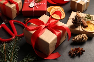 Photo of Beautiful gift boxes and Christmas decorations on black table, closeup