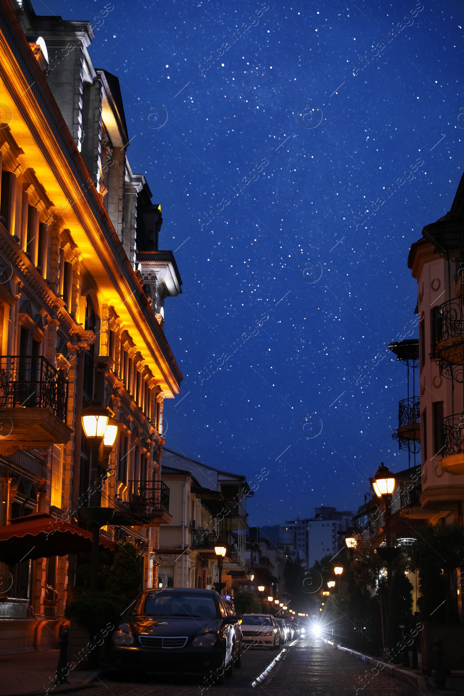 Photo of Beautiful cityscape with glowing streetlights, cars and illuminated building on starry night