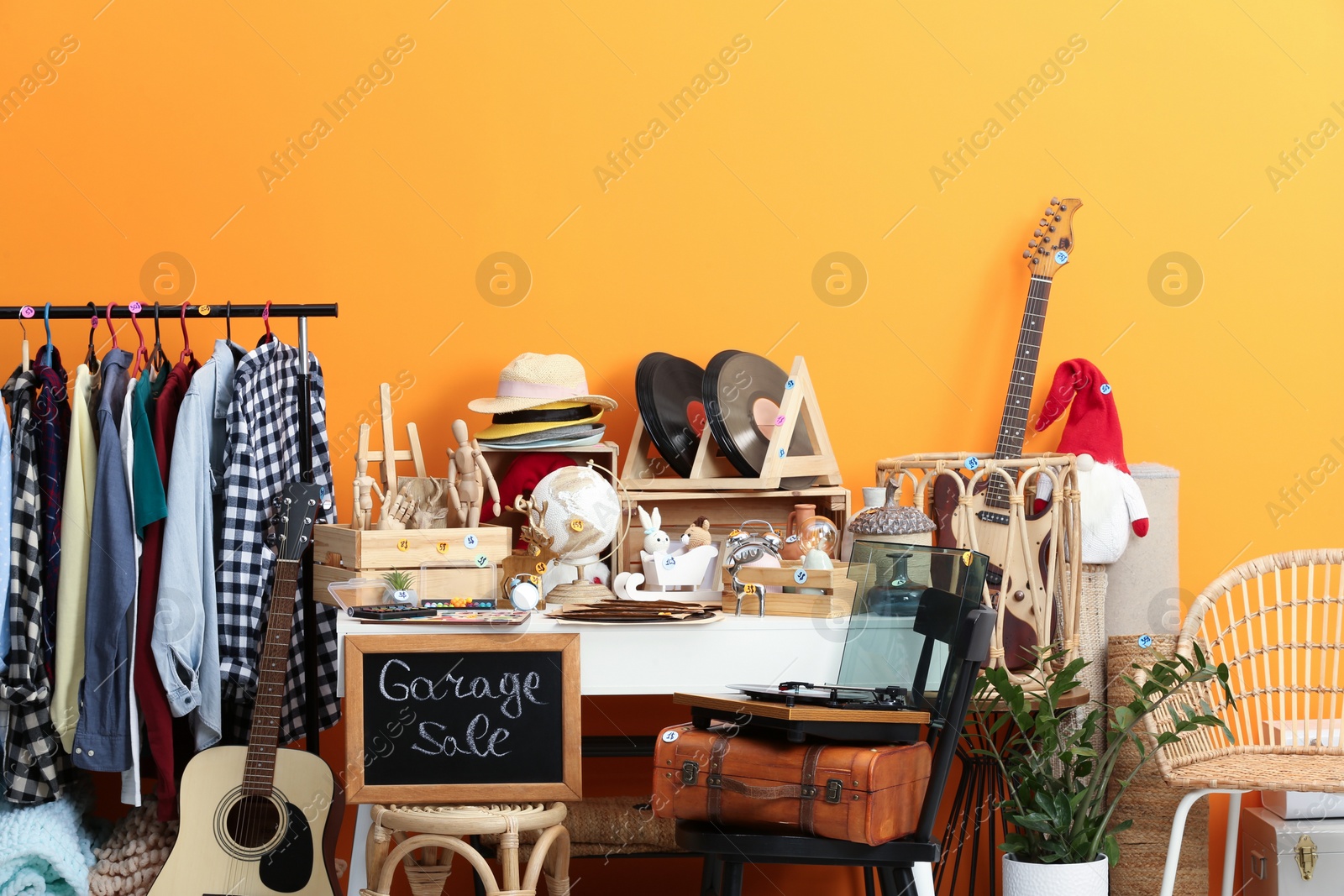 Photo of Sign Garage Sale written on blackboard near many different stuff