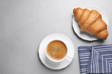 Photo of Tasty fresh croissant and coffee on light grey table, flat lay. Space for text