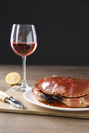 Photo of Delicious crab served with lemon and wine on wooden table