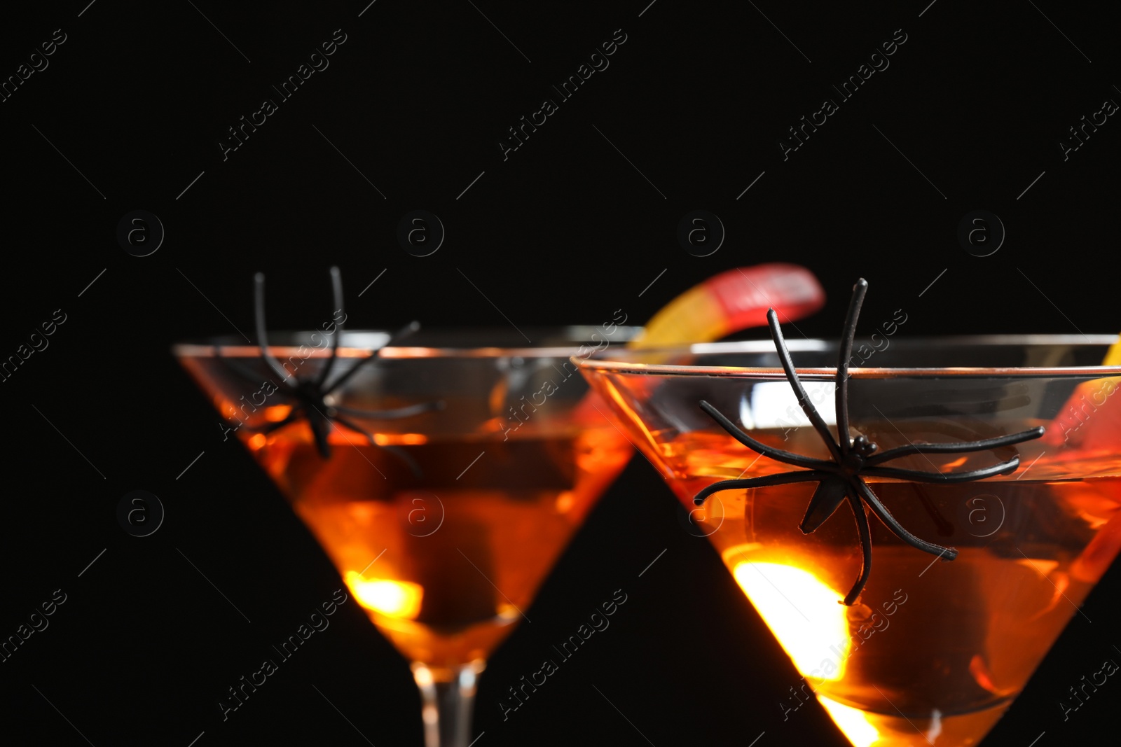 Photo of Decorated glasses with drinks on black background, closeup. Halloween celebration