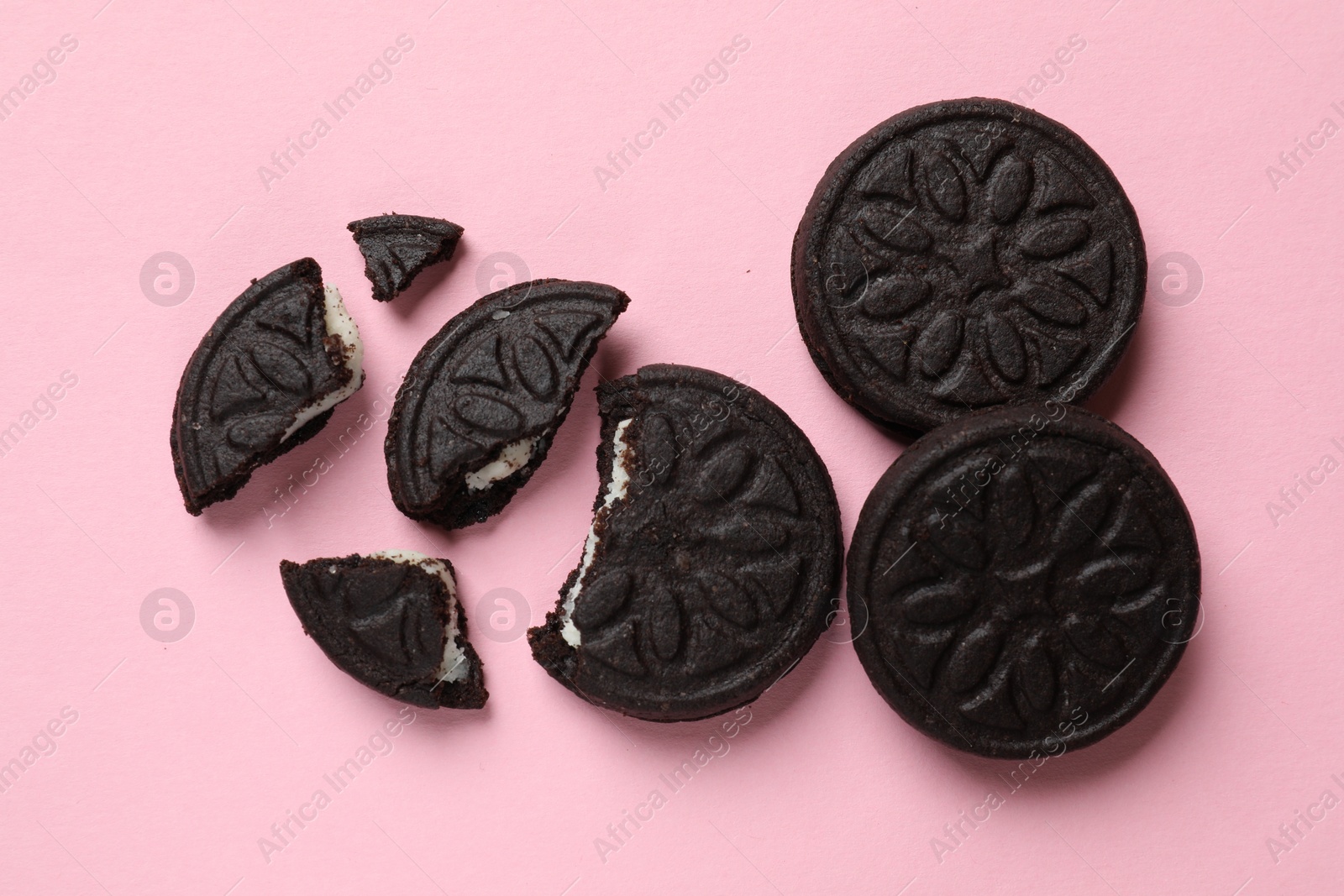 Photo of Tasty sweet sandwich cookies on pink background, flat lay