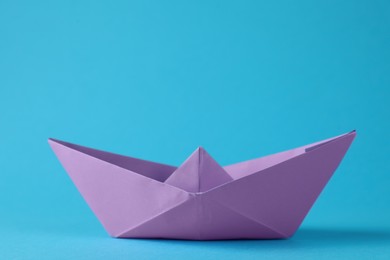 Photo of Handmade violet paper boat on light blue background. Origami art