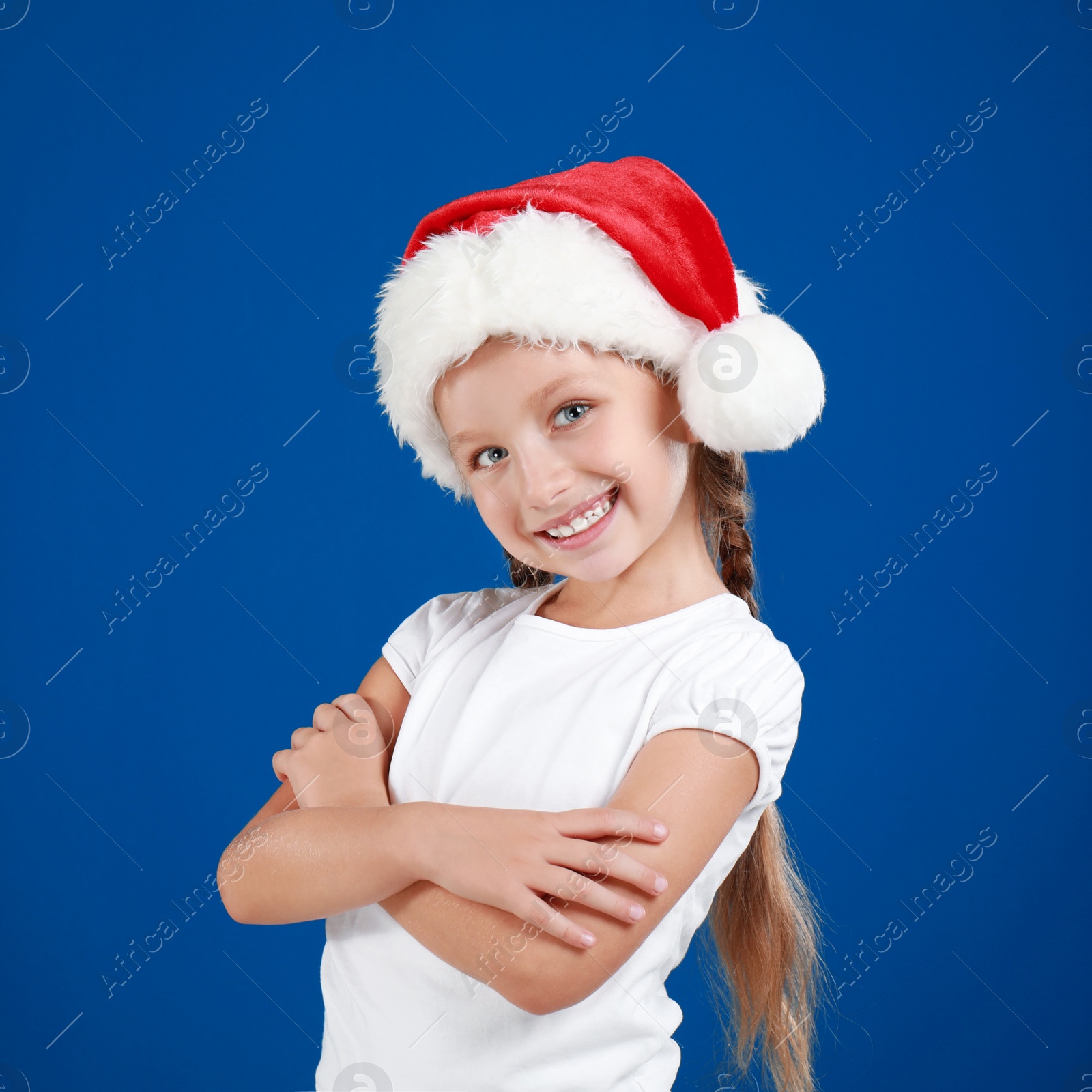 Image of Happy little child in Santa hat on blue background. Christmas celebration