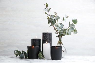Photo of Burning candles and green branches on marble table