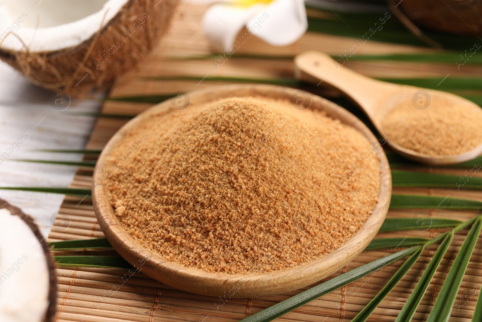 Photo of Coconut sugar, palm leaves and bamboo mat on wooden rustic table, closeup