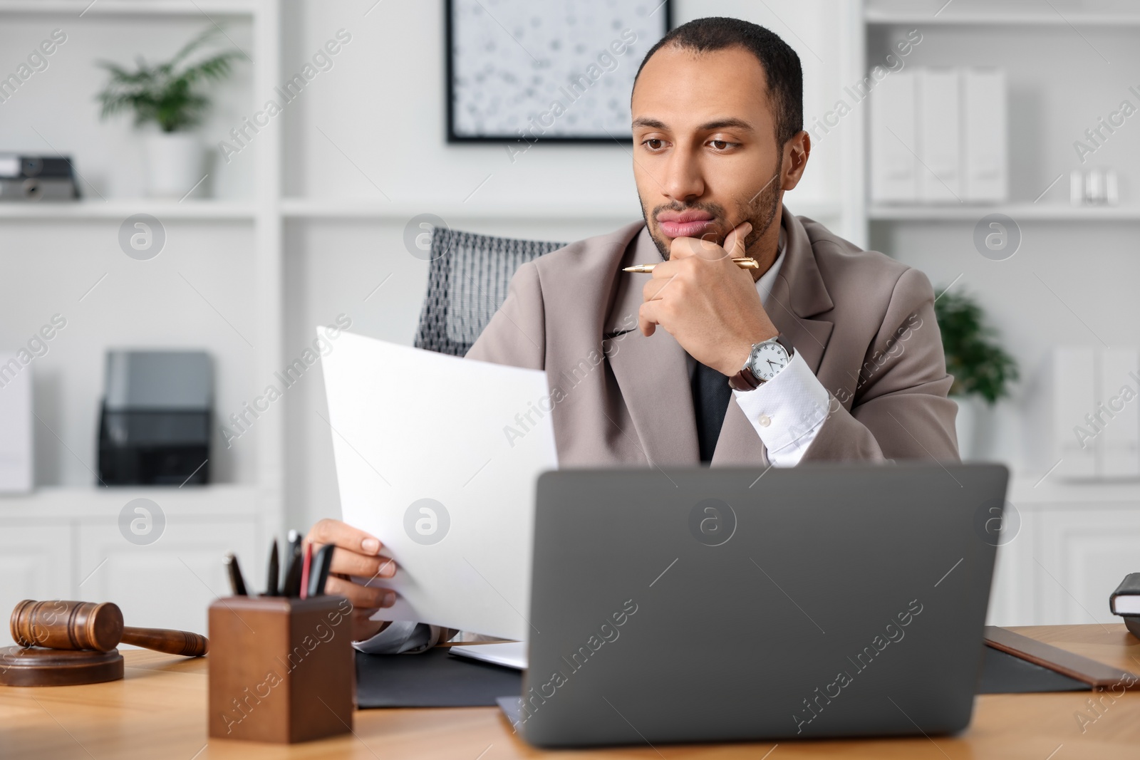 Photo of Confident lawyer working with document at table in office