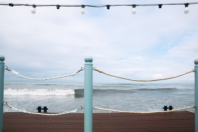 Picturesque view of sea with waves behind pier fence